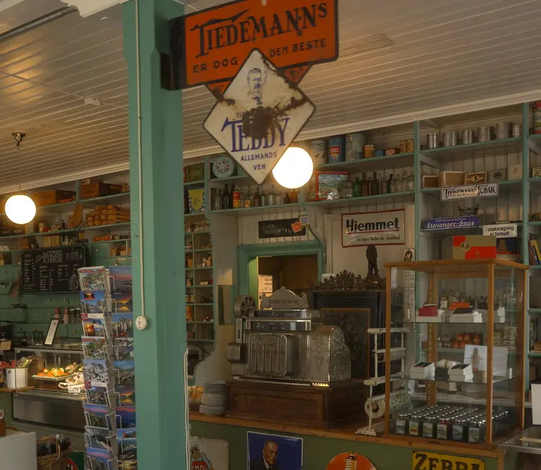 Innenaufnahme eines historischen norwegischen Kaufmannsladens auf den Lofoten mit alten Regalen, Kassen, Retro-Werbeschildern und traditionellen Waren. Das Bild zeigt eine authentische Museumsatmosphäre aus früheren Zeiten.