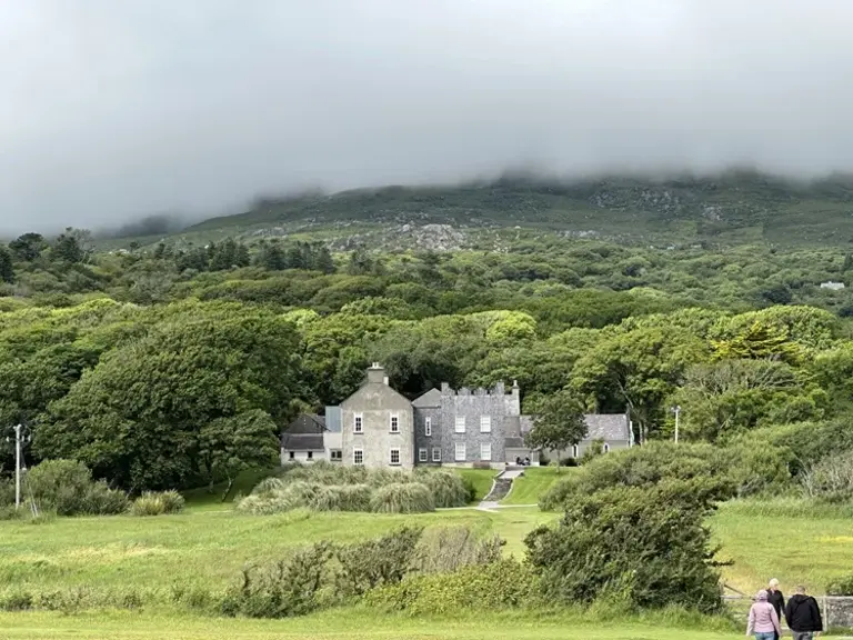 Derrynane House: Ein historisches Landgut im mystischen Irland entdecken Das historische Derrynane House in County Kerry, Irland, liegt idyllisch eingebettet in einer üppig grünen Wald- und Hügellandschaft, deren Gipfel in mystischem Nebel verschwinden und zu einer unvergesslichen Reise in die irische Kultur und Natur einladen.