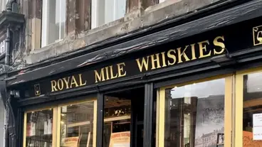 Royal Mile Whiskies: Schottlands berühmten Whisky in Edinburgh erleben Die Fassade des berühmten Fachgeschäfts "Royal Mile Whiskies" an der historischen Royal Mile in Edinburgh, Schottland, lädt mit ihrem eleganten gold-schwarzen Schriftzug Reisende und Kenner zu einer kulturellen und kulinarischen Entdeckungsreise in die Welt des schottischen Whiskys ein.