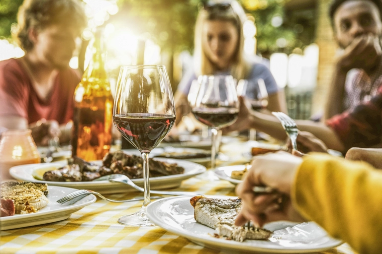 Freunde genießen ein gemeinsames Abendessen mit Rotwein im Freien – geselliges Beisammensein in Italien.