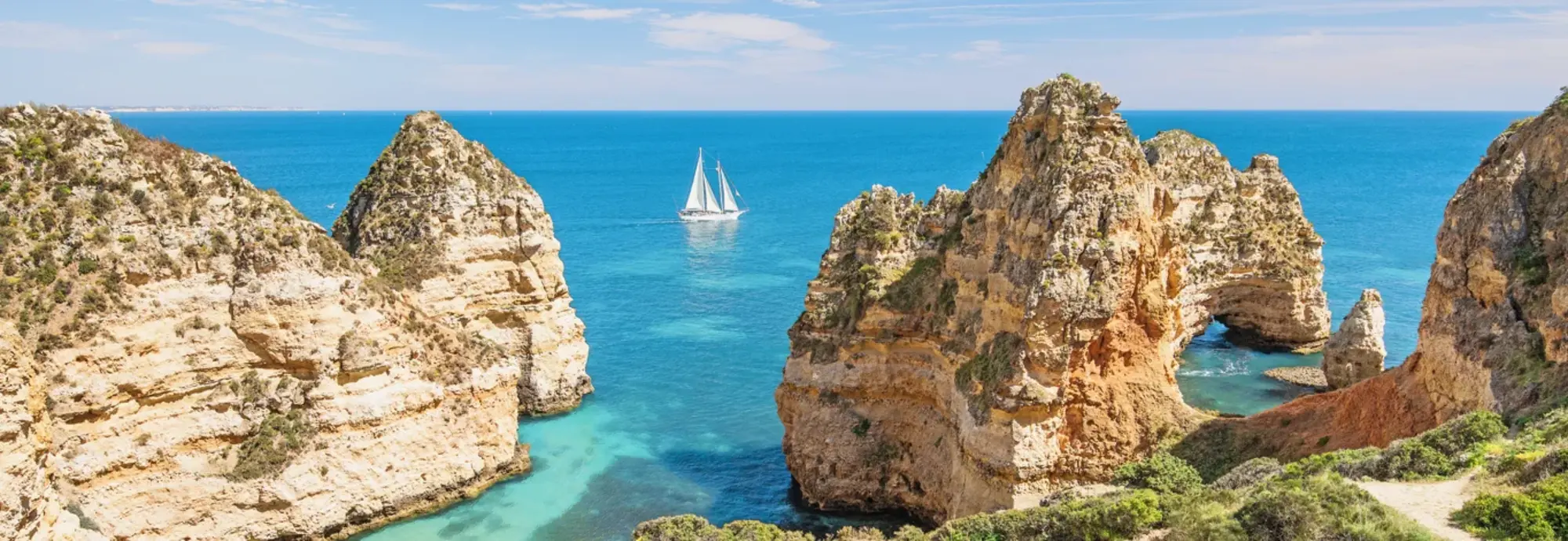 Das Bild zeigt zerklüftete Felsen und blaues Meer in Portugal. Der Ort heißt Ponta da Piedade und dieser liegt direkt am Atlantik. Es ist ein richtiges Highlight in einem Portugal Urlaub.