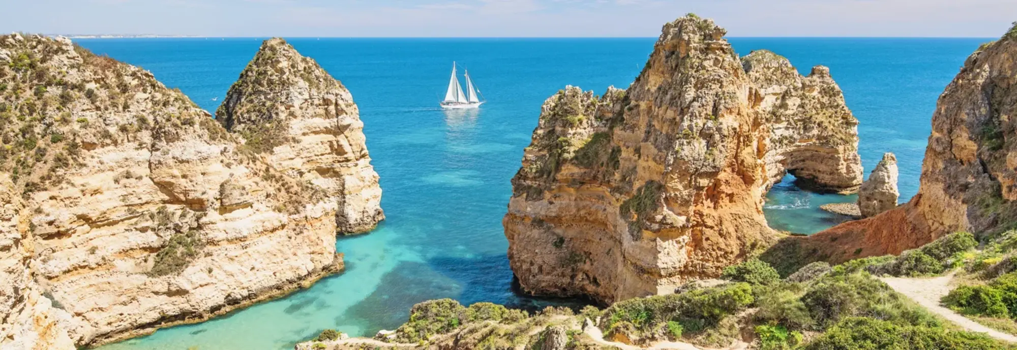Das Bild zeigt zerklüftete Felsen und blaues Meer in Portugal. Der Ort heißt Ponta da Piedade und dieser liegt direkt am Atlantik. Es ist ein richtiges Highlight in einem Portugal Urlaub.