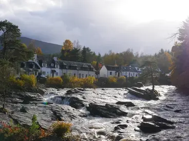 Malerisches Killin: Schottlands Natur an den wilden Falls of Dochart Gerne, hier sind der SEO-optimierte Titel und der barrierefreie Alt-Text für dein Bild: SEO-Titel: Malerisches Killin: Schottlands Natur an den wilden Falls of Dochart Alt-Text: Die wilden Stromschnellen der Falls of Dochart fließen durch das malerische Dorf Killin in den schottischen Highlands, wo traditionelle Häuser am Ufer stehen und die herbstliche Natur zu einer unvergesslichen Reise zu dieser beeindruckenden Sehenswürdigkeit in Schottland einlädt.