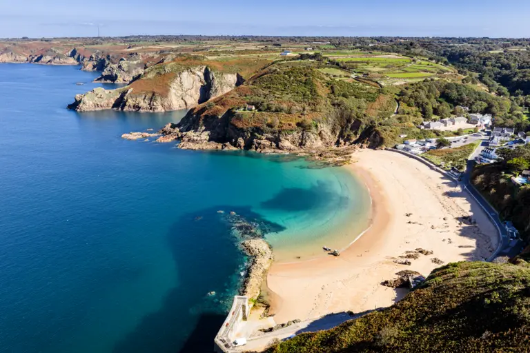 Grève de Lecq Zu sehe ist hier eine weite Landschaft mit einen Wunderschönen Gelben Strand welcher direkt an ein Dorf grenzt