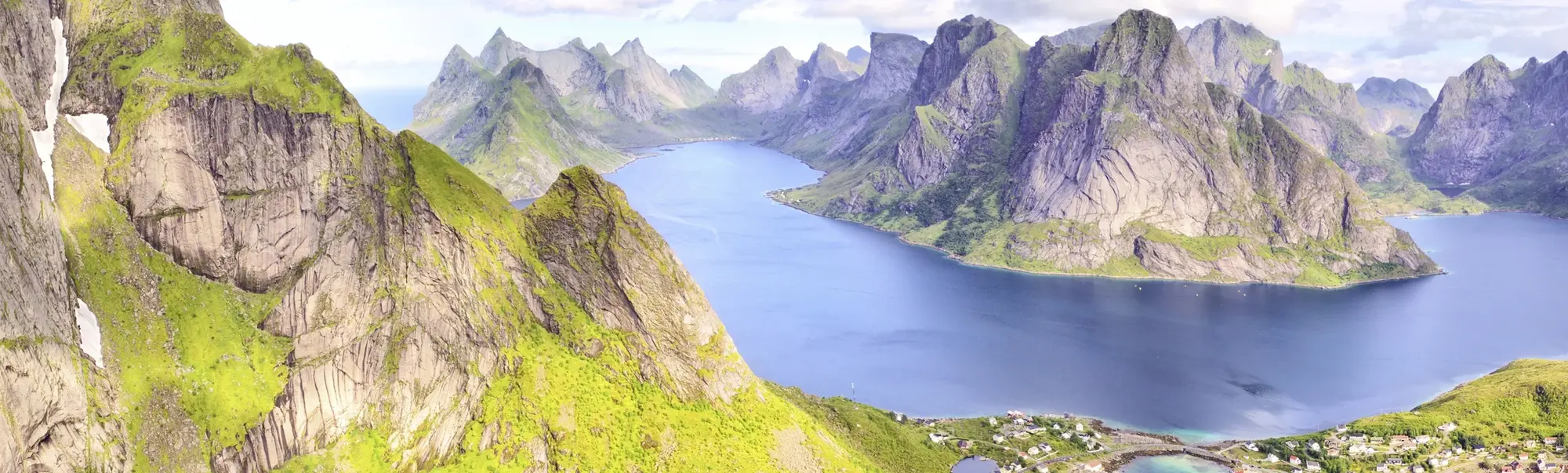 Atemberaubendes Panorama der Lofoten-Inseln - Norwegens spektakuläre Fjordlandschaft Weitwinkelaufnahme der Lofoten-Inseln in Norwegen mit schroffen Bergen, tiefblauem Fjordwasser und vereinzelten Schneefeldern. Eindrucksvolles Naturpanorama mit klarer Luft und ruhiger Atmosphäre.