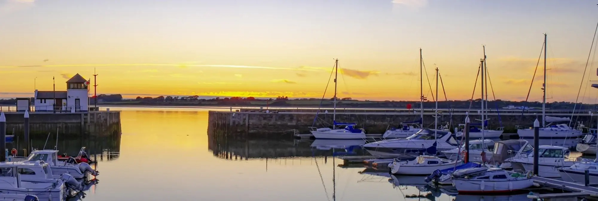 Das historische Caernafon Castle erhebt sich am Ufer des Menai Straits in Nordwales. Die mächtigen Türme und Mauern spiegeln sich im ruhigen Wasser des Hafens. Diese eindrucksvolle Sehenswürdigkeit gilt als Symbol walisischer Geschichte und ist ein beliebtes Ziel für Kulturinteressierte, die Weise auf einer Reise oder im Urlaub entdecken möchten.