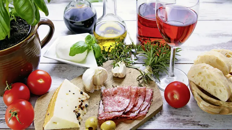 Aufschnittplatte mit Salami, Käse, Oliven, Tomaten, Knoblauch und Olivenöl – typische italienische Zutaten für Antipasti.