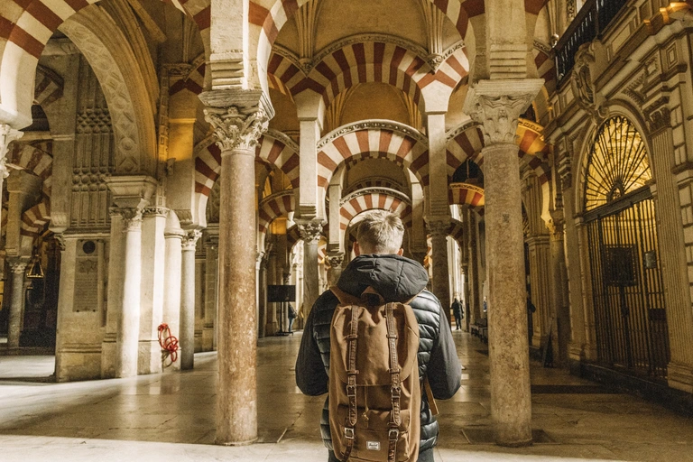 Innenraum der Mezquita in Córdoba mit Besucher Person mit Rucksack steht im Innenraum einer historischen Moschee mit Bögen und Säulen, vermutlich die Mezquita in Córdoba