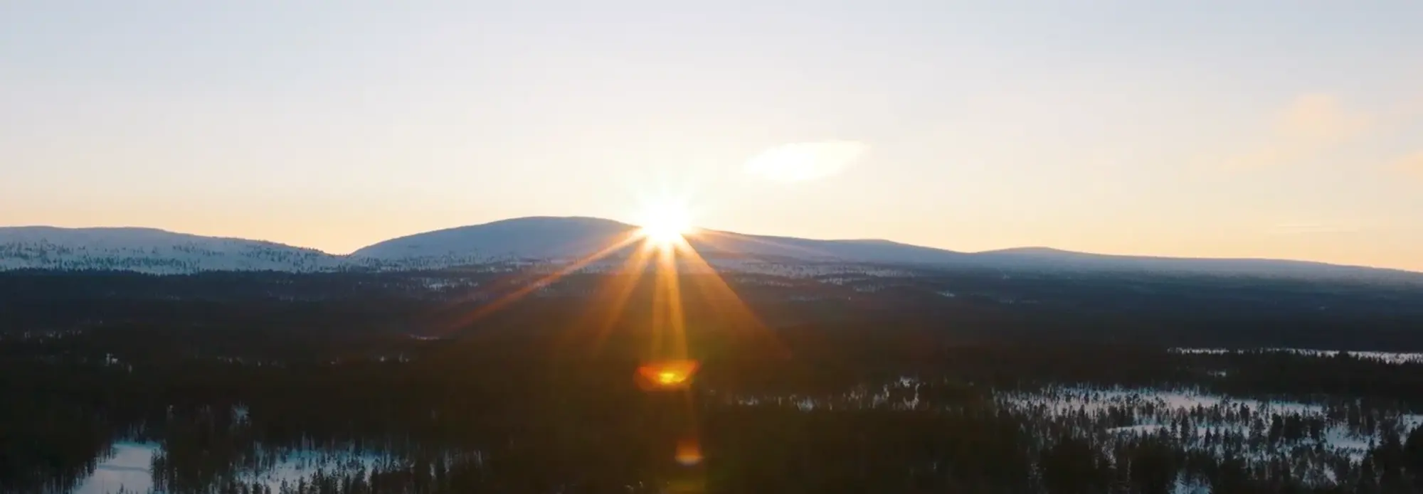 Wintersonne über Lappland: Magischer Sonnenaufgang in der finnischen Arktis Ein magischer Sonnenaufgang taucht die weite Winterlandschaft von Finnisch-Lappland in goldenes Licht, während die Sonne über den schneebedeckten Fjells und dunklen Wäldern aufgeht und die unberührte Natur zu einem unvergesslichen Abenteuer auf einer Reise in die Arktis einlädt.