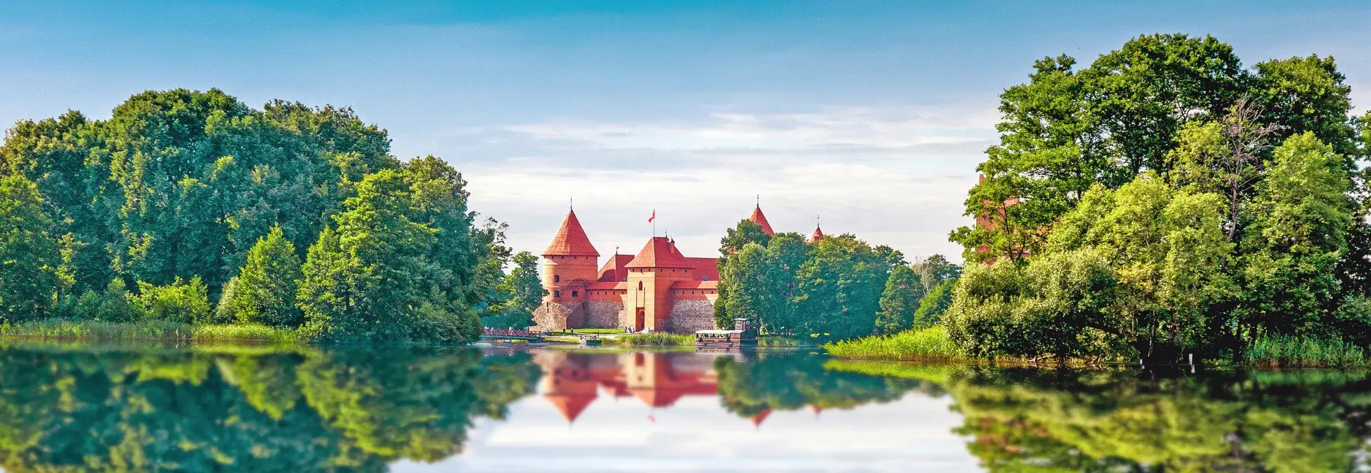 Die imposante Wasserburg Trakai in Litauen liegt malerisch auf einer Insel im Galvė-See und spiegelt sich im ruhigen Wasser wider, umgeben von dichten Wäldern.