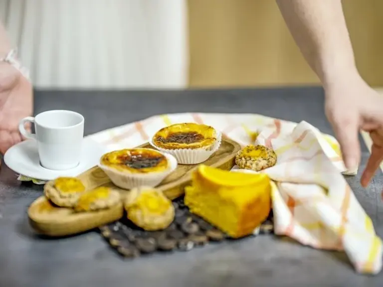 Süßspeisen Madeira – Bolo do Mel und Pasteis de Nata Das Bild zeigt typische Süßspeisen von Madeira und Portugal: Bolo do Mel (Honigkuchen), Pasteis de Nata und andere Gebäckvariationen, serviert mit einer Tasse Kaffee. Die Szene steht für die süße Seite der kulinarischen Tradition Madeiras und lädt zum Genießen im Urlaub ein.