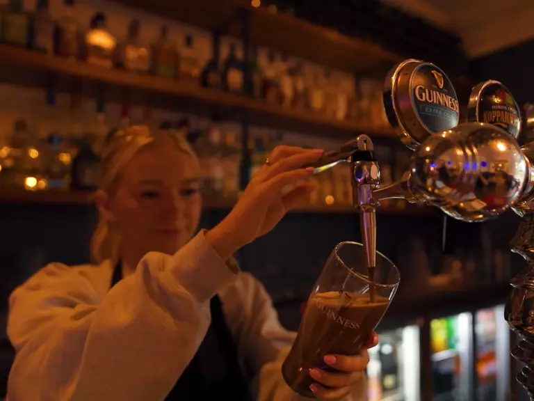 Barkeeperin zapft ein frisches Guinness in einem traditionellen irischen Pub – authentisches Erlebnis der Pubkultur in Irland.