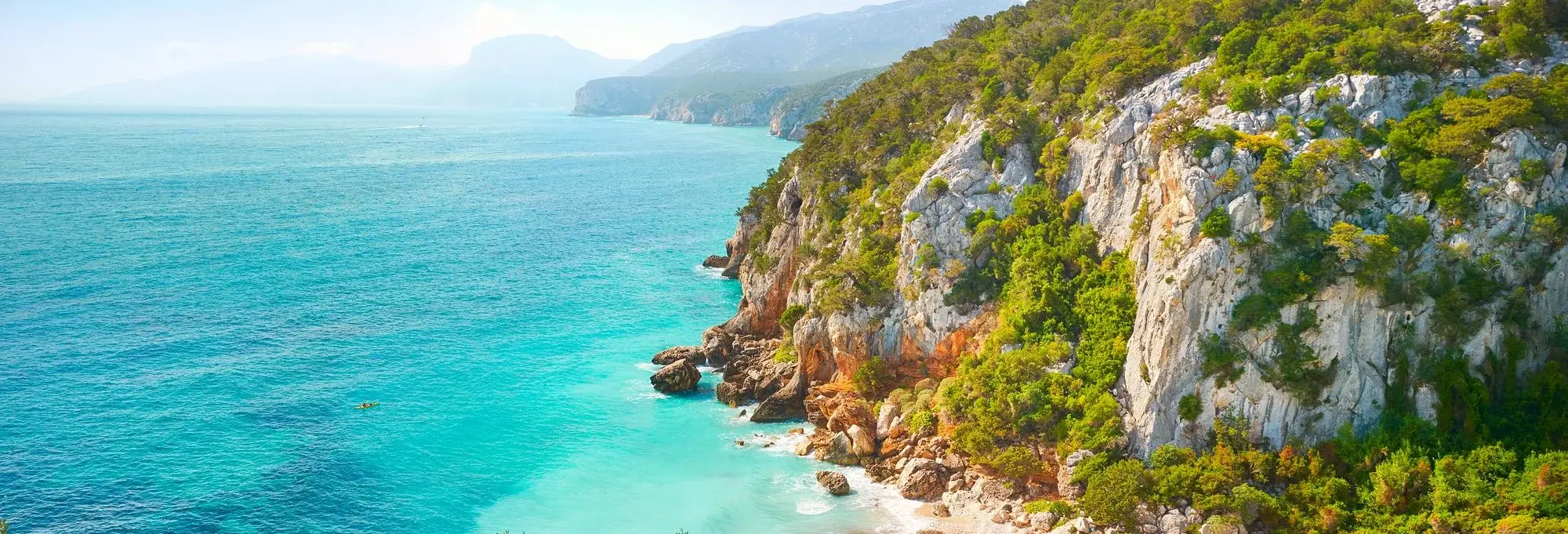 Traumhafte Steilküste auf Sardinien mit türkisblauem Meer, grüner Vegetation und Felsen – ideale Kulisse für Urlaub in Italien.
