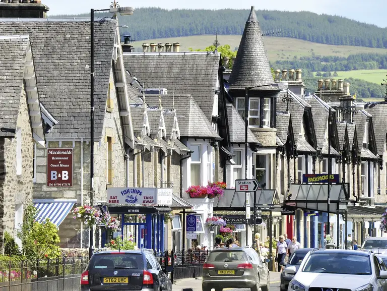 Pitlochry - Malerische Kleinstadt in den schottischen Highlands Lebhafte Hauptstraße mit traditionellen Gebäuden, kleinen Geschäften, Pubs und Blumen in Pitlochry. Typisches Beispiel schottischer Kleinstadtarchitektur im Herzen der Highlands.