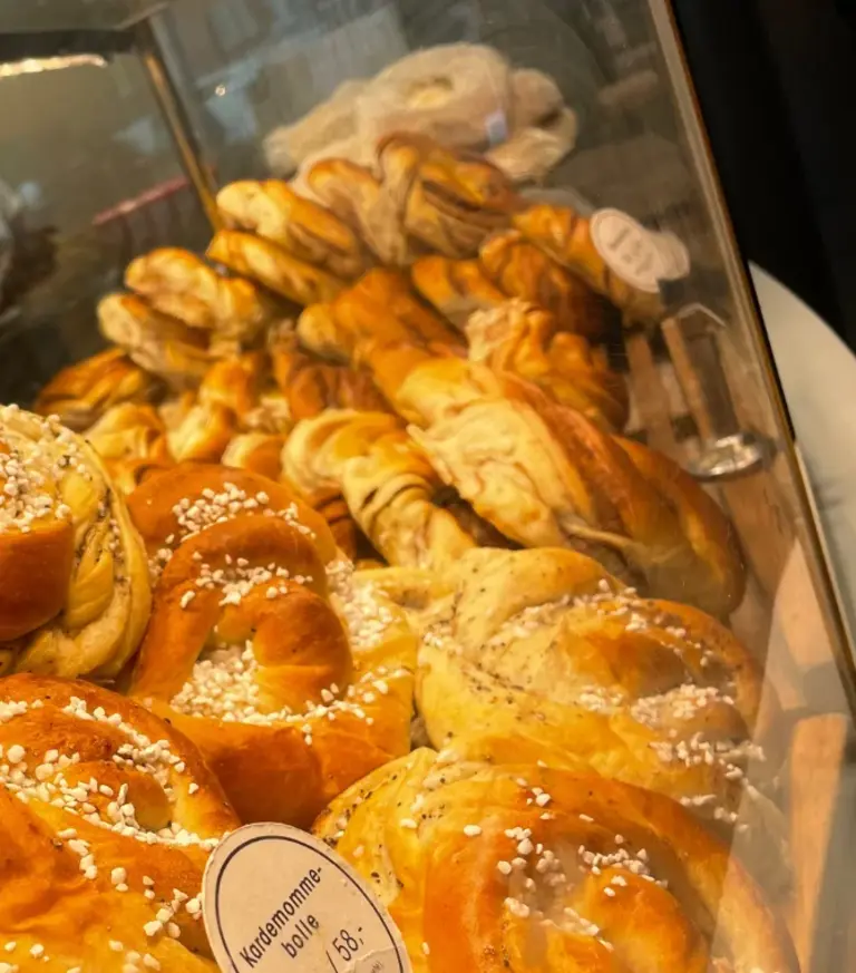 Norwegische Kardamom-Schnecken Auf diesem Bild ist eine Nahaufnahme von frisch gebackenen Kardamom-Schnecken („Kardemommebolle“) in der Auslage einer norwegischen Bäckerei zu sehen. Das Hefegebäck, bestreut mit Hagelzucker, ist eine typische und beliebte skandinavische Spezialität.