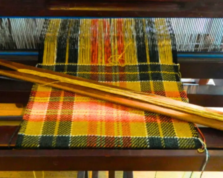 Tartan Webstuhl Webstuhl auf dem ein gelb-roter Tartan-Stoff gewebt wird