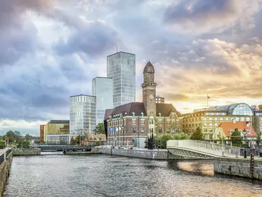 Aufnahme von einen Fluss in der Stadt Malmö, welcher von großen Häusern aus Glas umgeben ist.