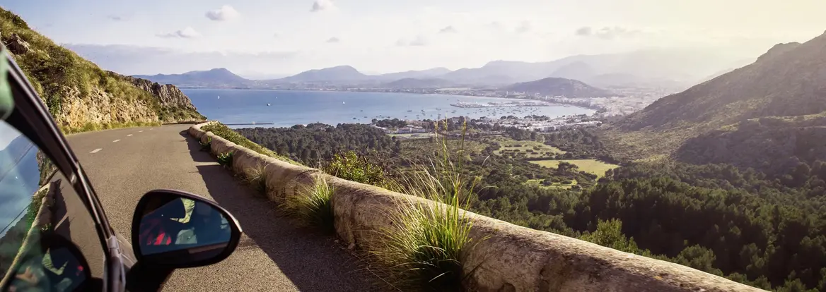 Panoramafahrt auf Fuerteventura - Küstenstraße mit Blick auf Meer und Vulkanlandschaft Das Bild zeigt eine kurvenreiche Küstenstraße auf Fuerteventura auf den Kanarischen Inseln in Spanien, aufgenommen aus einem Auto mit freiem Blick über grüne Täler, vulkanisch geprägte Hügel und den tiefblauen Atlantik, während warmes Licht eine ruhige und zugleich abenteuerliche Stimmung erzeugt, die typisch für einen Urlaub voller Reisen, Naturerlebnisse, Panoramaausblicke und Entdeckungen auf einer vielseitigen Insel ist.
