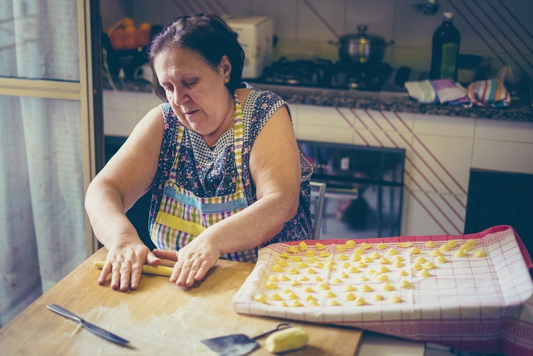 Italienische Frau bereitet handgemachte Pasta in einer Küche zu – traditionelle Kochkunst Italiens.